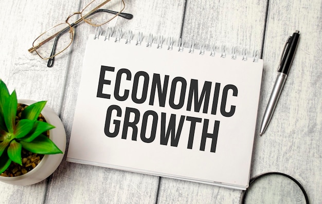 Economische groei tekst op een notitieblok met pen bril en plant