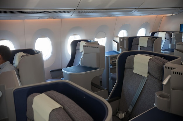 An economy class empty cabin of the airplane empty dark blue chairs opened portholes