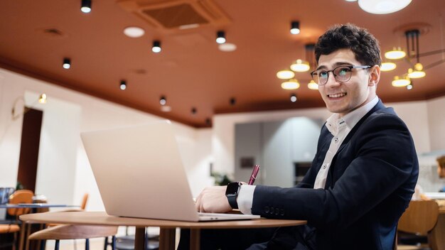 Econoom man in glazen pak aan het werk op kantoor schrijft een bericht naar een partner per e-mail