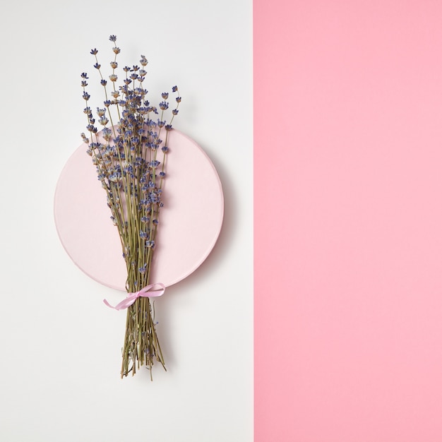 Ecotak van lavendelbloemen op een rond keramisch bord op een muur van de duotoonpastelkleur, exemplaarruimte. Bovenaanzicht.