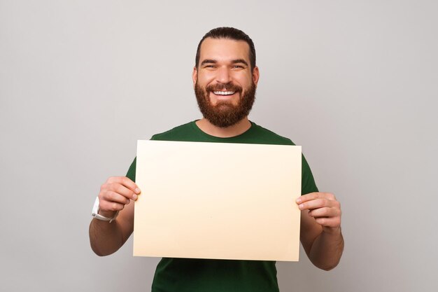 Ecstatic bearded is holding a blank card with copy space for your message