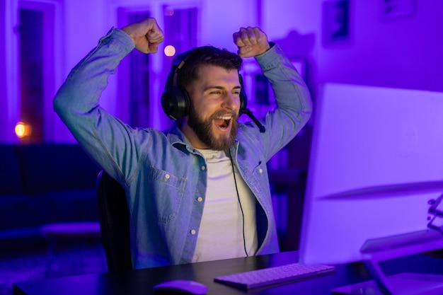 Photo ecstatic man celebrating game victory in neon light