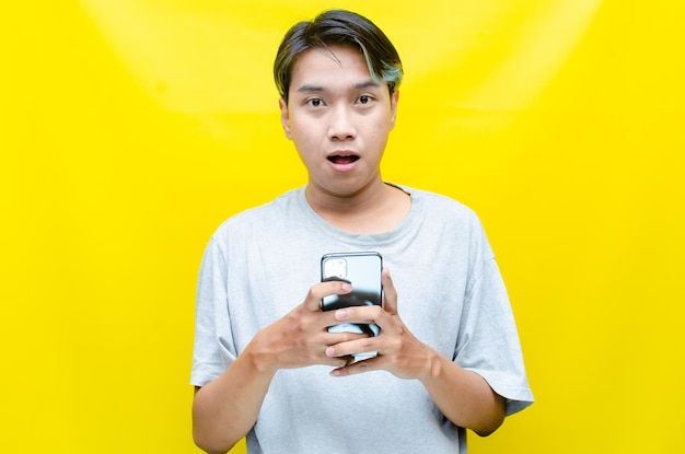 ecstatic A young handsome Asian man being surprised after reading message on his smartphone