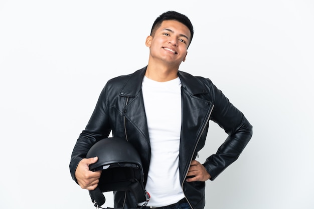 Ecudorian man with a motorcycle helmet isolated on white wall posing with arms at hip and smiling