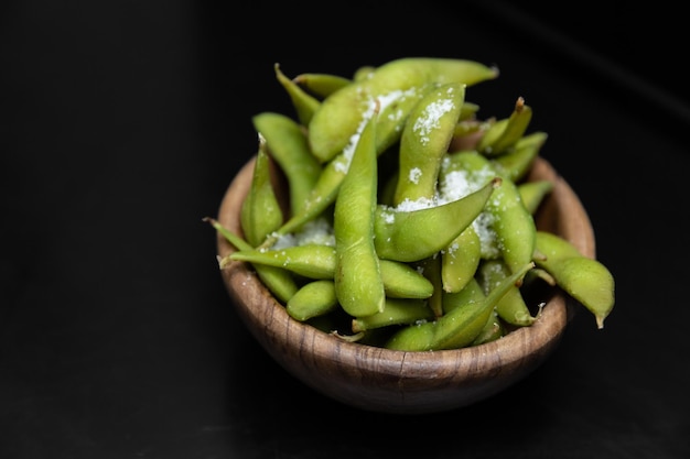 黒の背景に分離された暗いボウルで提供される海の塩と枝豆豆のサラダ レストラン食品日本のキッチン