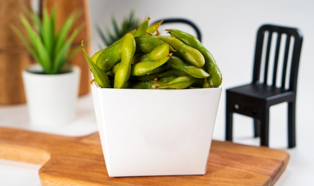 Edamame in a paper box served on a wooden cutting board