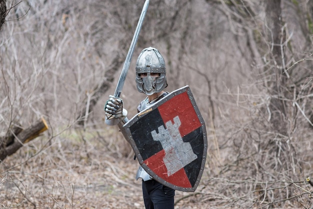 Edele krijger Portret van een middeleeuwse krijger of ridder in harnas en helm met schild en zwaard poseren