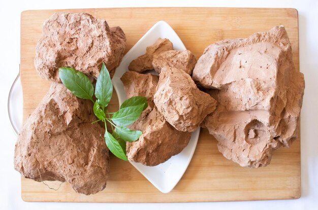 Premium Photo  Edible brown clay stones with green leaves on a white  background