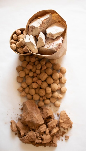 Edible caramel clay stones in brown bag with white and brown clay stones on a white background