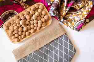 Photo edible caramel clay stones on a wooden plate with a bag on a white background