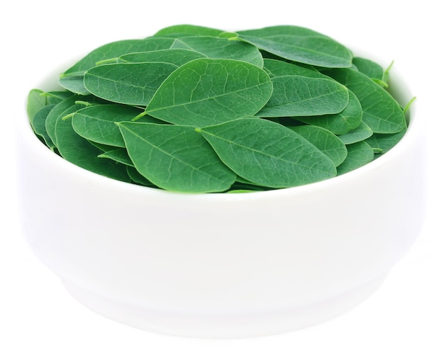 Edible moringa leaves in a bowl over white background