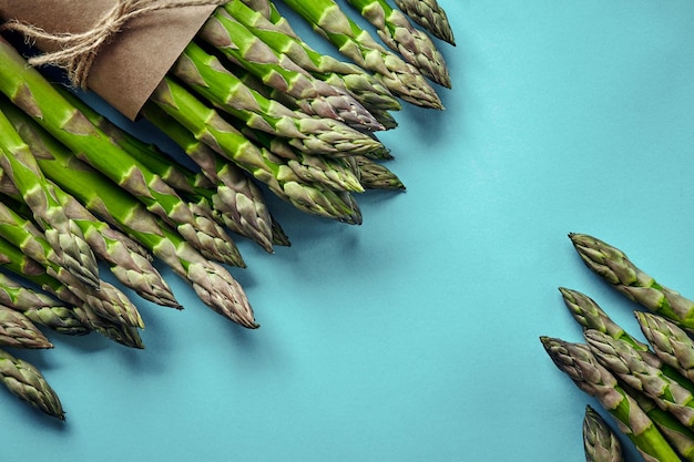 An edible raw stems of asparagus on blue background