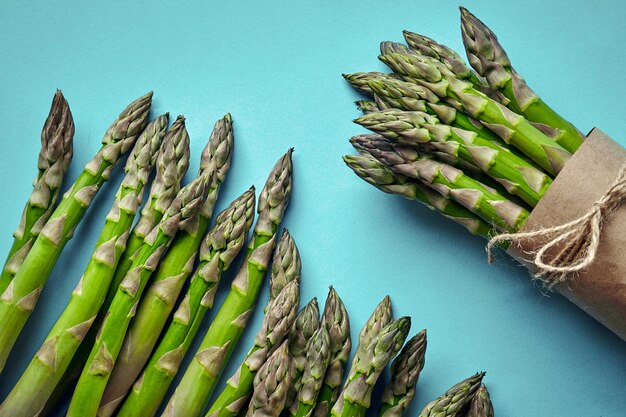 An edible raw stems of asparagus on blue background