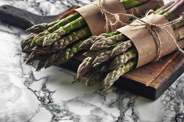 An edible raw stems of asparagus on a marble background