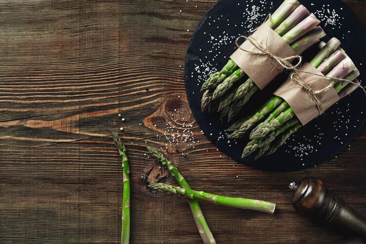 An edible raw stems of asparagus on a wooden background