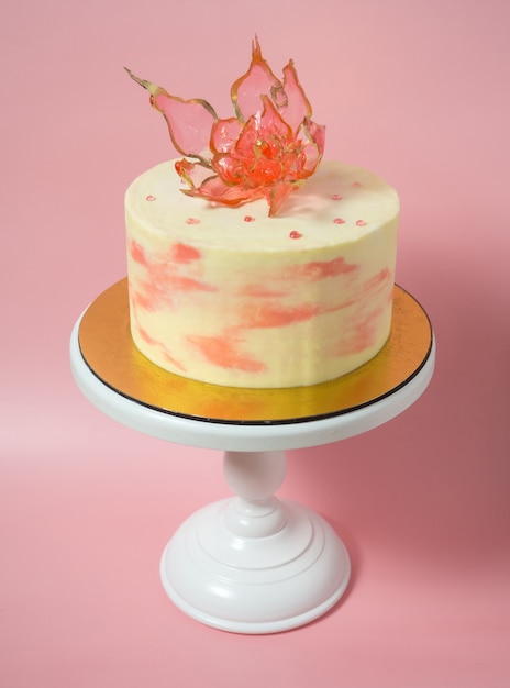 An edible red flower on top of an isomalt cake on a pink background