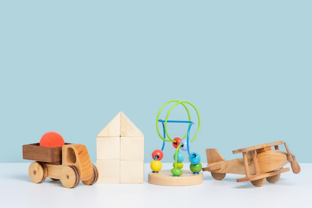 Educatief milieuvriendelijk speelgoed voor kleuters Houten speelgoed auto vrachtwagen vliegtuig doolhof en constructor kubussen op een blauwe achtergrond Kopieer ruimte