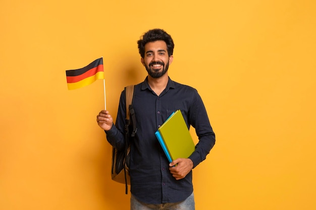 Education abroad portrait of happy young indian student guy holding german flag
