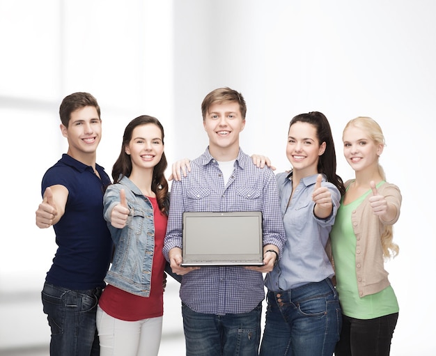 education, advertisement and new technology concept - smiling students with laptop computer blank screen showing thumbs up