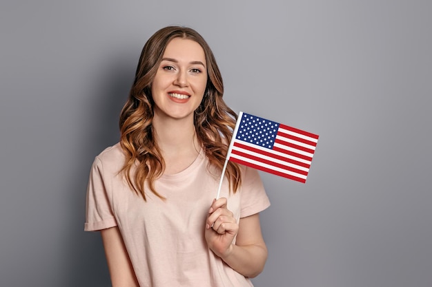 Education in America Caucasian young student girl holds a small american flag isolated overorange background girl holding USA flag 4th of july independence day