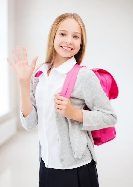 Фото Концепция образования и школы - счастливая и улыбающаяся девочка-подросток со школьной сумкой