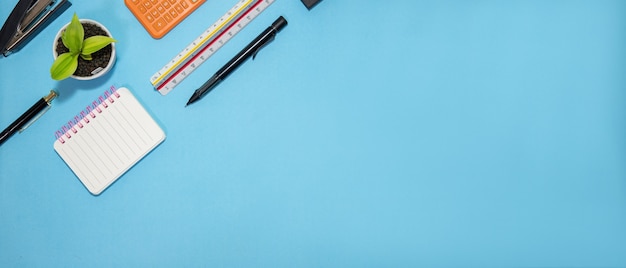 Education or back to school concept. top view of colorful\
school supplies with books, color pencils, calculator, pen cutter\
clips and apple on blue pastel background. flat lay.