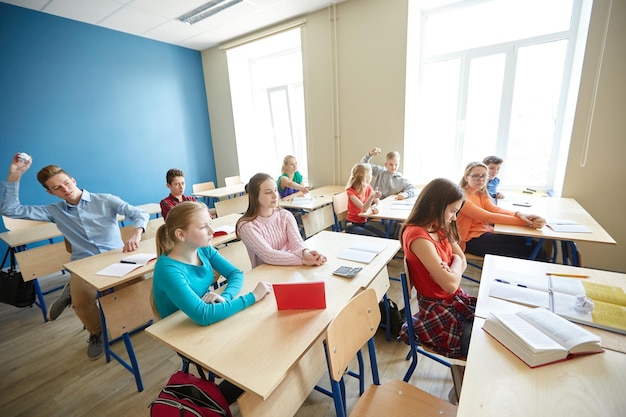 education, bullying, conflict, problem and people concept - students gossiping behind classmate back at school