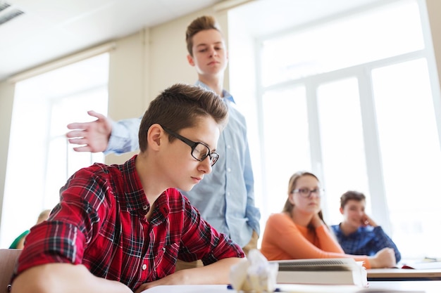 education, bullying, social relations and people concept - classmate offending at student boy at school