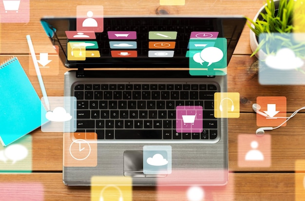 Фото Концепция образования, бизнеса, мультимедиа и технологий - крупный план ноутбука с иконками меню на экране деревянного стола