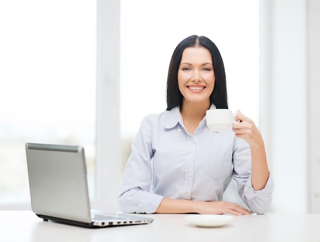 education, business and technology concept - smiling businesswoman or student with laptop computer and coffee