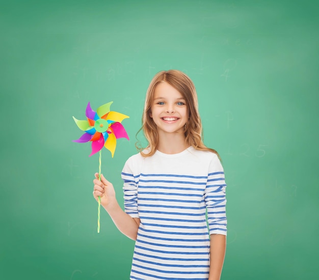 education, childhood and ecology concept - smiling child with colorful windmill toy