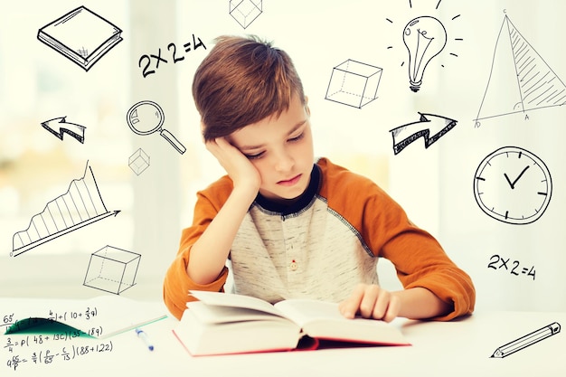 education, childhood, people, homework and school concept - bored student boy reading book or textbook at home over mathematical doodles