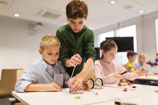 教育、子供、技術、科学、人のコンセプト – ロボット学校の授業でロボットを作る幸せな子供のグループ