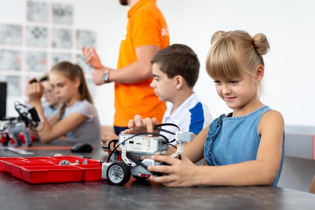 Istruzione, bambini, tecnologia, scienza e concetto di persone - gruppo di bambini felici con computer portatili che costruiscono robot alla lezione di robotica