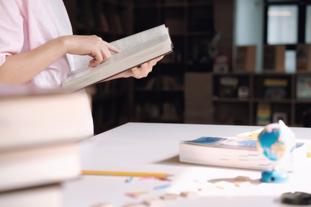 Education concept. Girl reading a book in library of school.