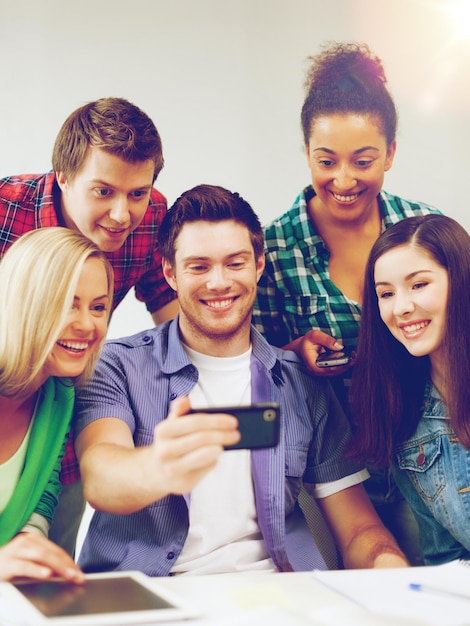 education concept - group of students looking into smartphone at school