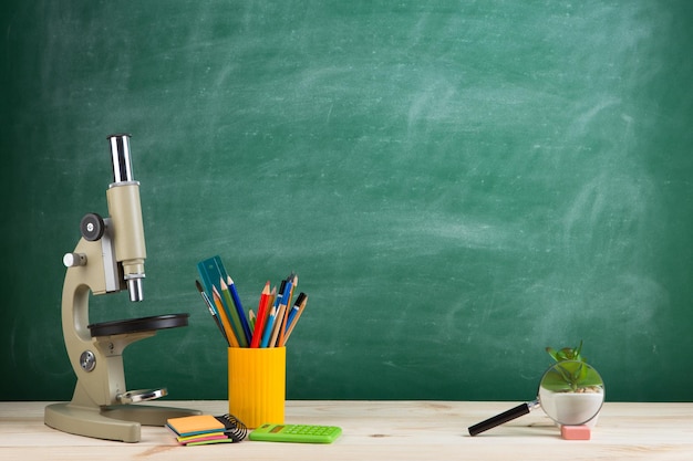 Education concept microscope on the desk in the auditorium blackboard background