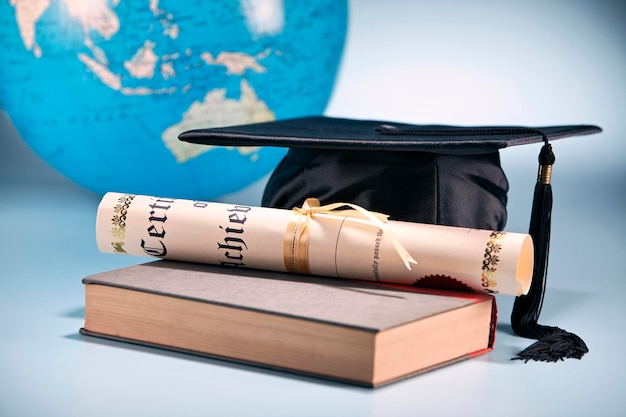 Education concept mortar board certificate and book with globe