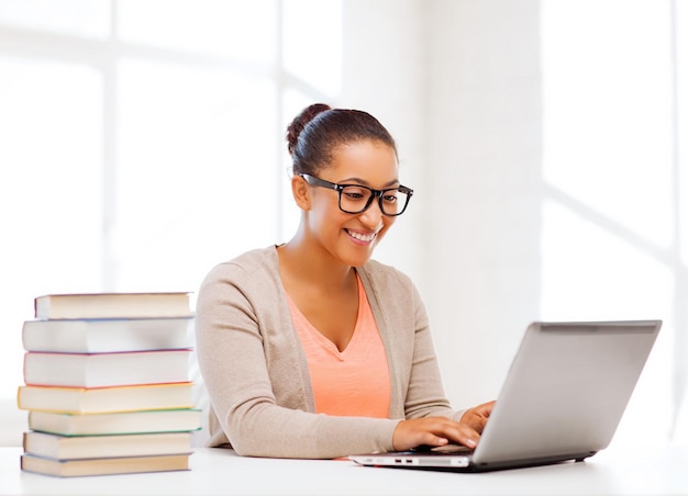 education concept - smiling international student girl with laptop at school