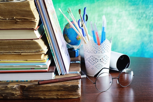 Foto concetto di educazione. una pila di libri di testo e un libro sulla scrivania con gli occhiali e un computer. mela e compiti della colazione della scuola