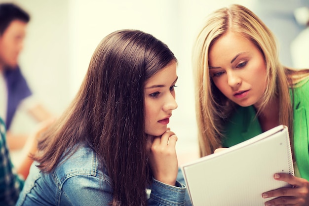 Photo education concept - student girls looking at notebook at school