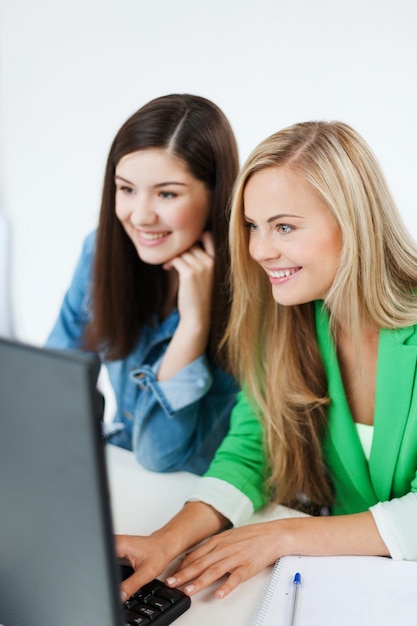 education concept - students looking at laptop at school