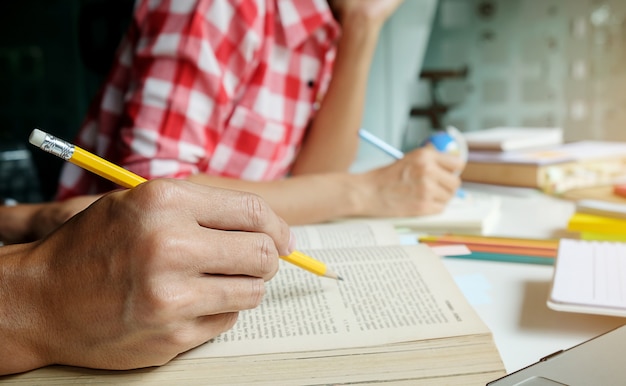 Concetto di educazione. studenti che studiano e brainstorming il concetto del campus. primo piano di studenti che discutono il loro tema sui libri di libri e la scrittura a notebook. messa a fuoco selettiva.