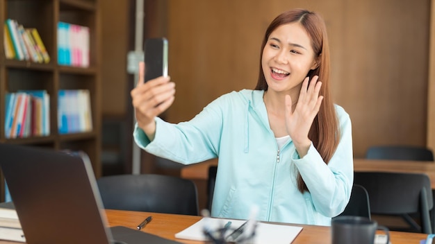 Education concept Teenage girl using smartphone to video call with friends after study tutorial