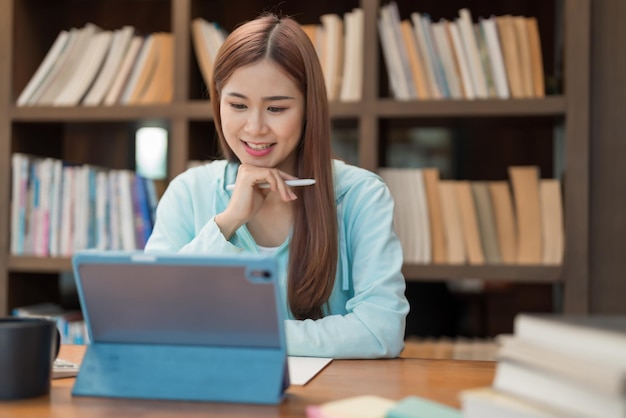 Education concept Teenage girl watching video math tutorial of tutor on tablet and taking notes