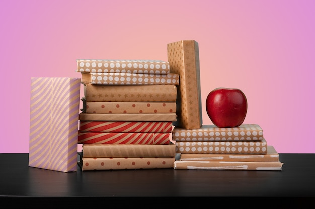 Education concept with stack of books on a table against colored background