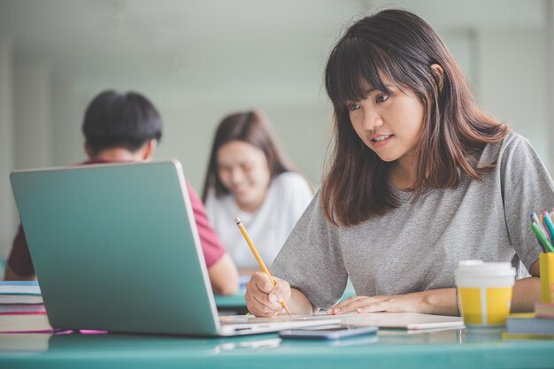 Education concept Young people students are happy to read the exam books on the table in university Asian women focus on books to prepare for final exams