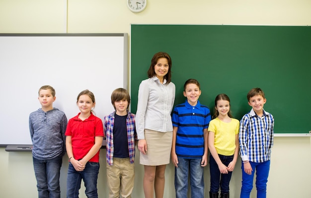 Photo education, elementary, gesture and people concept - group of school kids and teacher in classroom