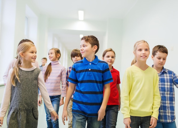 education, elementary school, drinks, children and people concept - group of smiling school kids walking in corridor