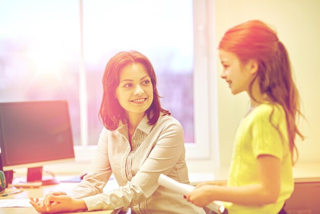 education, elementary school, learning, examination and people concept - school girl with notebook and teacher in classroom